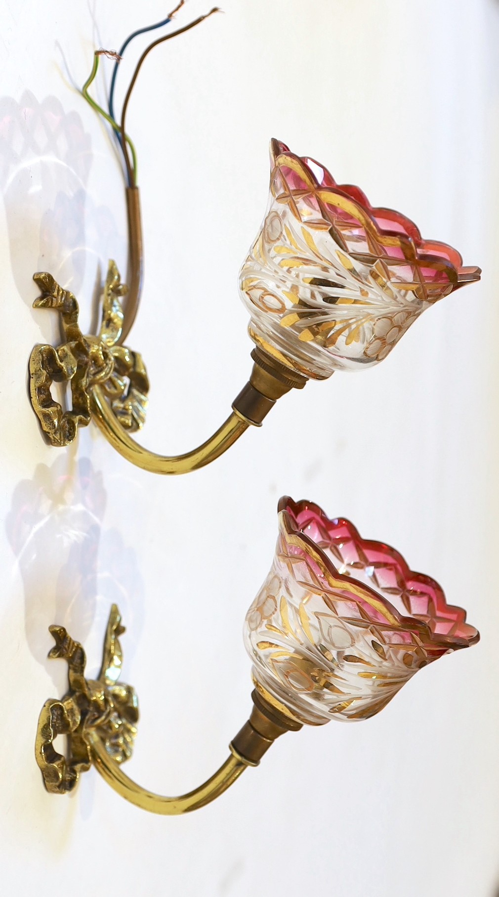 A pair of 1920s brass wall lights with frosted flame glass shades and a pair of brass ribbon back wall lights with lustre shades, height 14cm & height 12cm